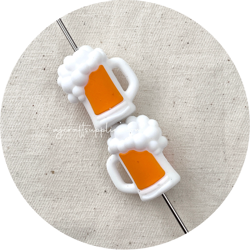 Two white beer mug-shaped silicone beads with orange liquid on a textured beige background